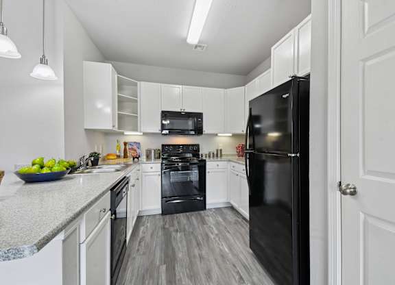 A black refrigerator is in a white kitchen.