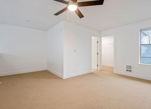 Empty carpeted bedroom with vaulted ceiling and ceiling fan at Six Oaks Apartments, Washington