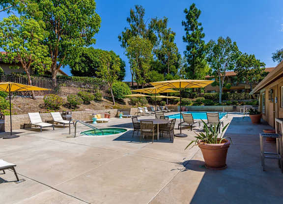 A pool area with a green pool and a yellow umbrella.