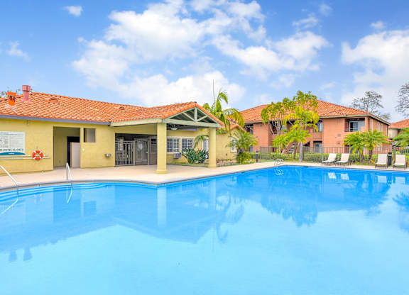 A swimming pool in front of a building with a red roof.
