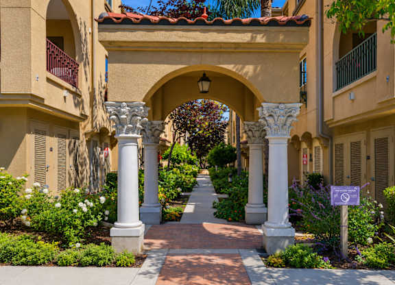 A pathway leads through a courtyard with a white archway and a purple sign.
