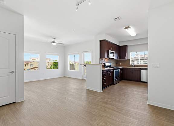 A spacious kitchen with wooden floors and white walls.