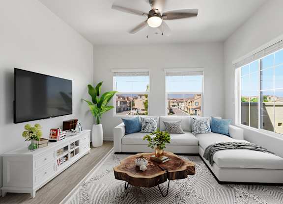 A living room with a white couch, a wooden coffee table, and a flat-screen TV mounted on the wall.