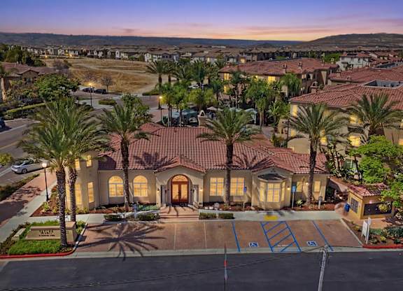 A large house with a driveway and palm trees in front.