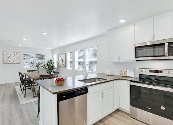 a kitchen with white cabinets and stainless steel appliances and a dining room table