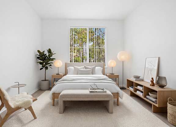 A bedroom with a large bed, a chair, and a plant.