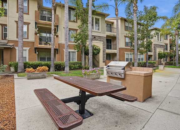 A brown picnic table sits in front of apartment buildings.