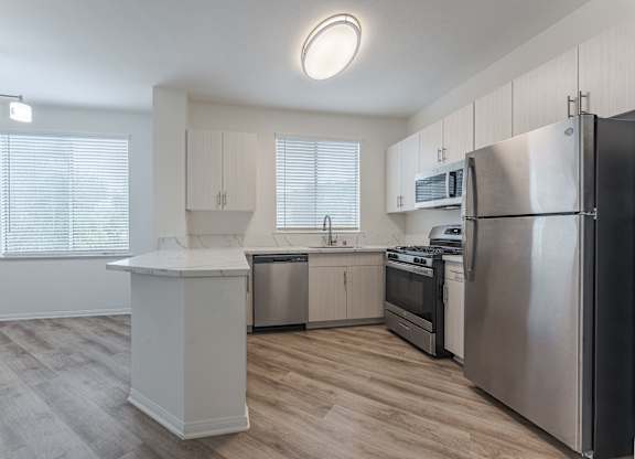 A modern kitchen with stainless steel appliances and wooden flooring.
