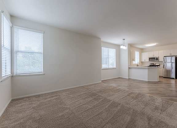 A spacious room with a kitchenette and a carpeted floor.