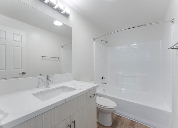 A white bathroom with a sink, toilet, and shower.