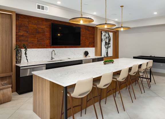 the kitchen has a large marble counter top and a long island with chairs