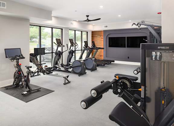 a gym with various exercise equipment and a tv in the corner