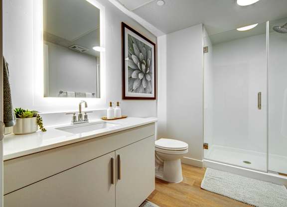 A white bathroom with a toilet, sink, and shower.