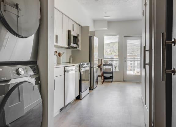 a kitchen with a washer and dryer and a door to a living room