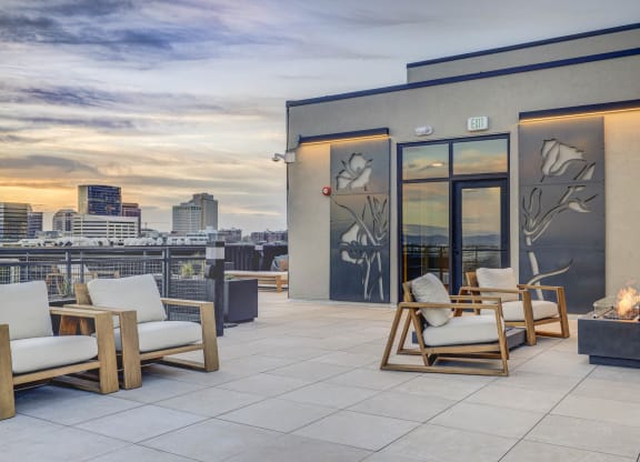 a roof deck with chairs and a view of the city