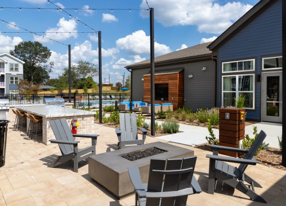 a patio with tables and chairs and a pool in front of a house