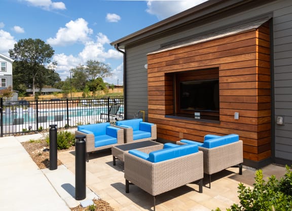 a patio with couches and a tv on the side of a house