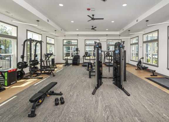 a gym with weights and cardio equipment in a building with windows