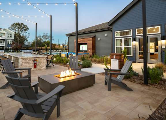A patio with a fire pit and chairs.
