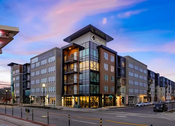 A modern apartment building with a glass facade and a sign that reads "TAGAGE".