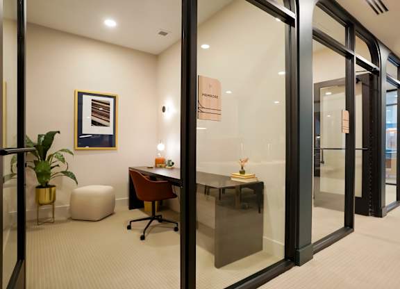 A modern office with glass walls and a plant on the desk.