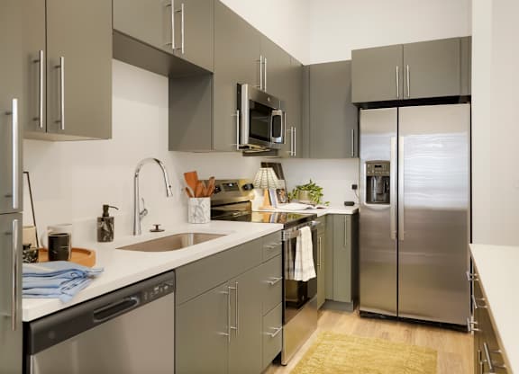 A modern kitchen with stainless steel appliances and grey cabinets.
