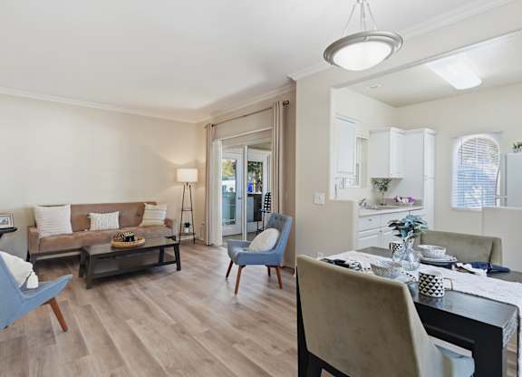 A modern living room with a brown sofa, a grey armchair, and a dining table set for two.
