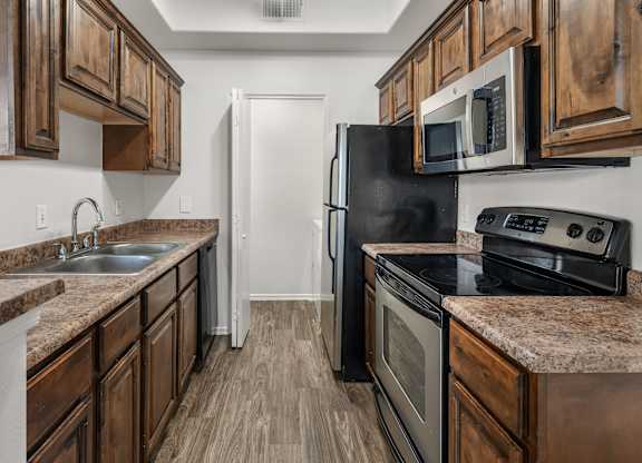 A kitchen with dark wood cabinets and a black refrigerator.