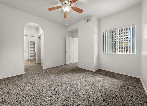 A spacious room with a ceiling fan and carpeted floor.
