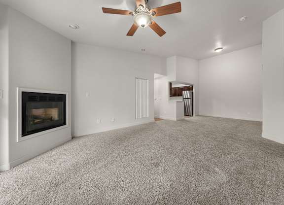 A spacious living room with a fireplace and a ceiling fan.