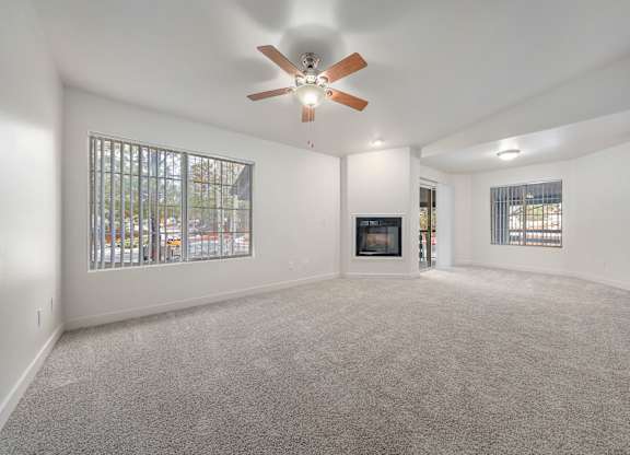 A spacious living room with a fireplace and a ceiling fan.