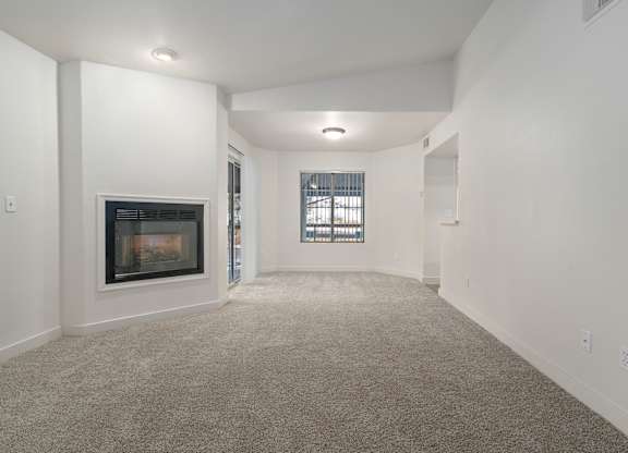 A spacious living room with a fireplace and a window.