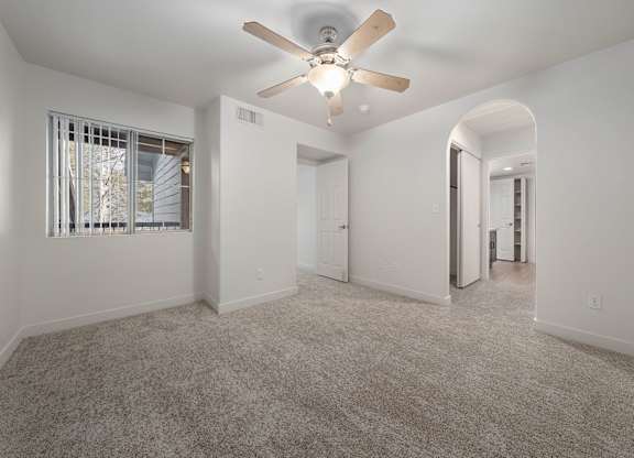 A spacious room with a ceiling fan and carpeted floor.