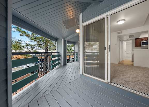 A wooden deck with a sliding glass door leading to a room.