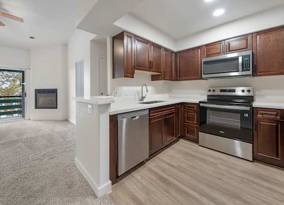 A modern kitchen with dark wood cabinets and stainless steel appliances.