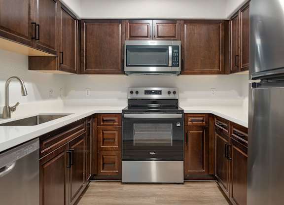 A modern kitchen with dark wood cabinets and stainless steel appliances.