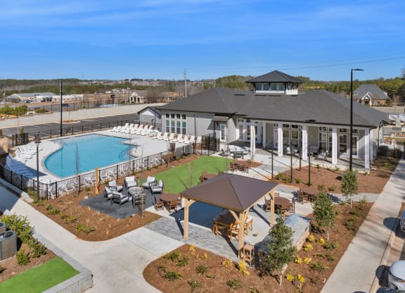 an aerial view of a resort style pool and clubhouse with tables and chairs