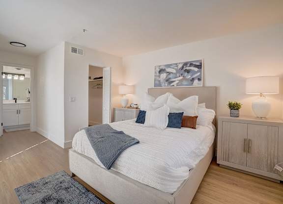 A bedroom with a large bed and a painting above it.