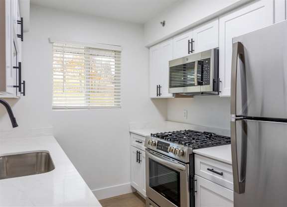A kitchen with white cabinets and stainless steel appliances.