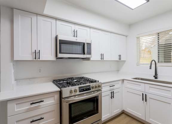 A kitchen with white cabinets and a stove top oven.