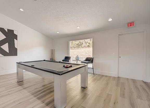 A pool table in a room with a chair and a painting.