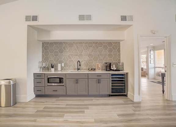 A modern kitchen with a grey backsplash and a trash can.