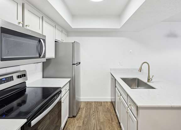 A kitchen with a black stove top oven and a stainless steel refrigerator.