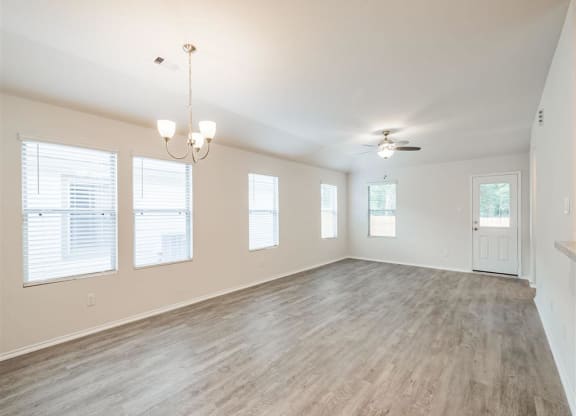 an empty living room with a ceiling fan and windows at The Village at Caney Mills, Conroe, Texas