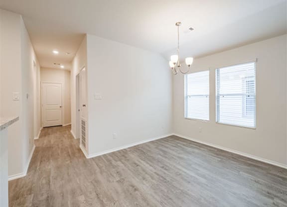 the living room and dining room of an empty home with wood flooring at The Village at Caney Mills, Conroe, Texas