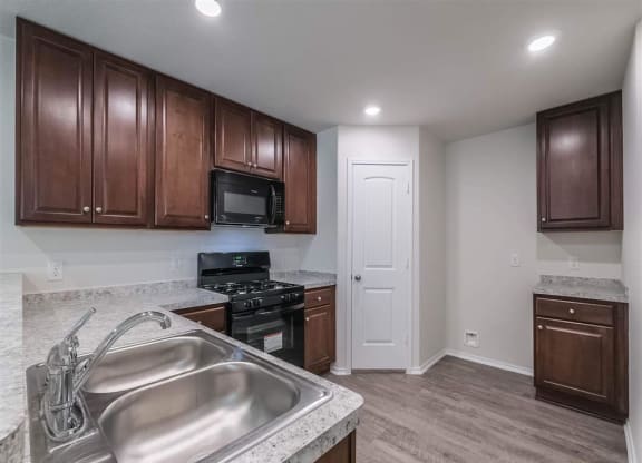 a kitchen with a sink and a stove and a microwave at The Village at Caney Mills, Texas