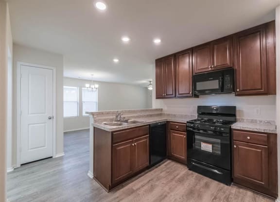 a kitchen with a stove and a sink and a microwave at The Village at Caney Mills, Conroe, Texas