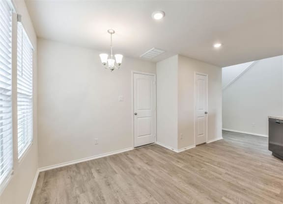 an empty living room with white walls and wood flooring at The Village at Caney Mills, Conroe