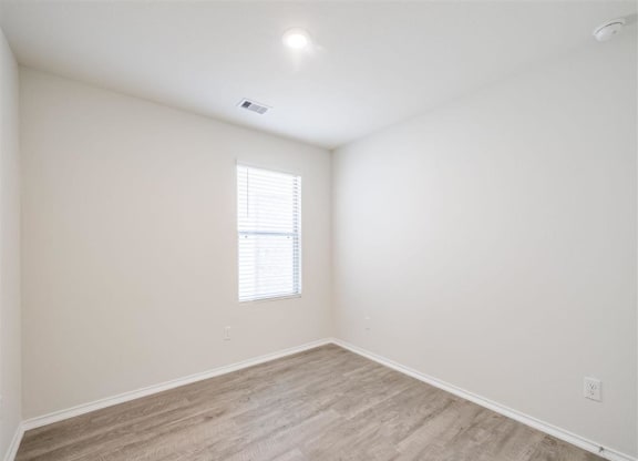 an empty room with wood flooring and a window at The Village at Caney Mills, Texas, 77303