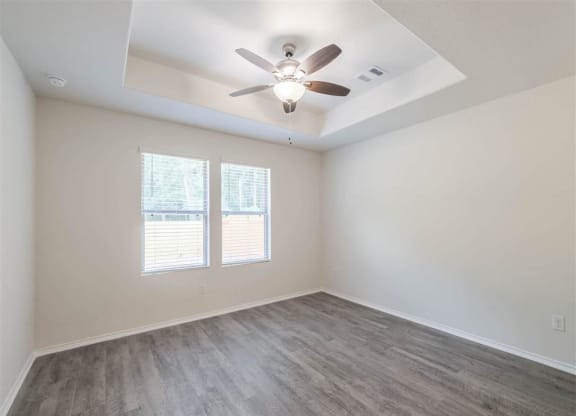 an empty living room with a ceiling fan and a window at The Village at Caney Mills, Conroe